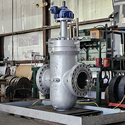 Silver industrial gate valve with blue actuator top in a workshop